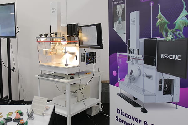 An NS CNC machine running on its stand at the NS CNC trade show booth