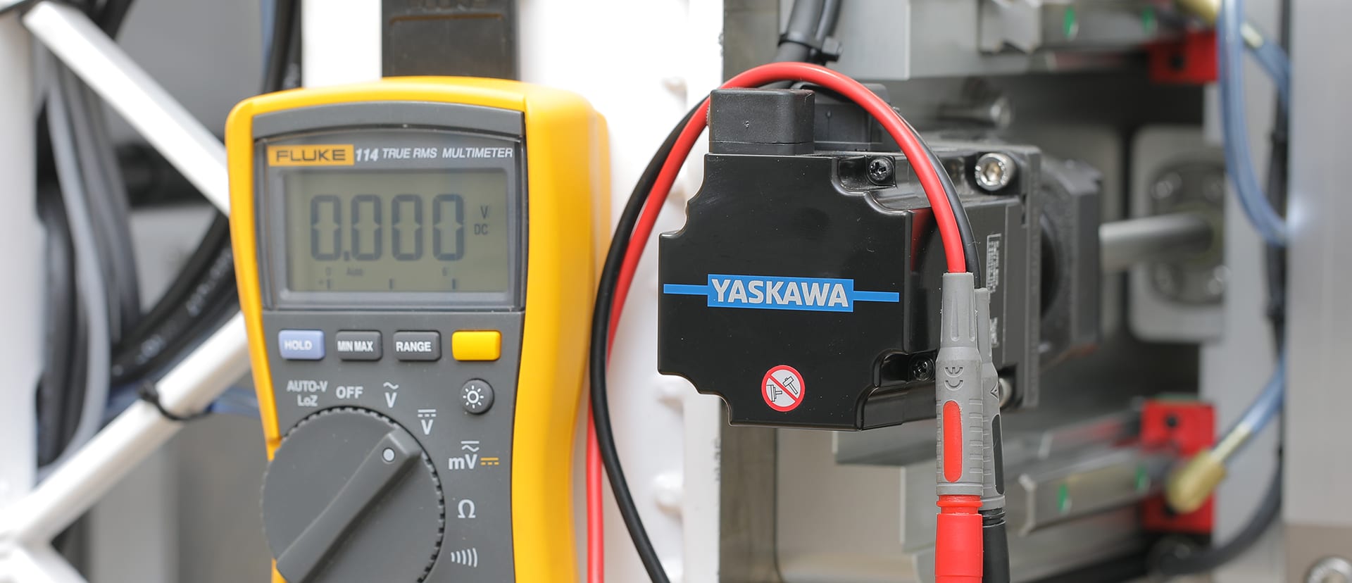 A Fluke multimeter testing the cable of a Yaskawa servo motor on an NS CNC machine