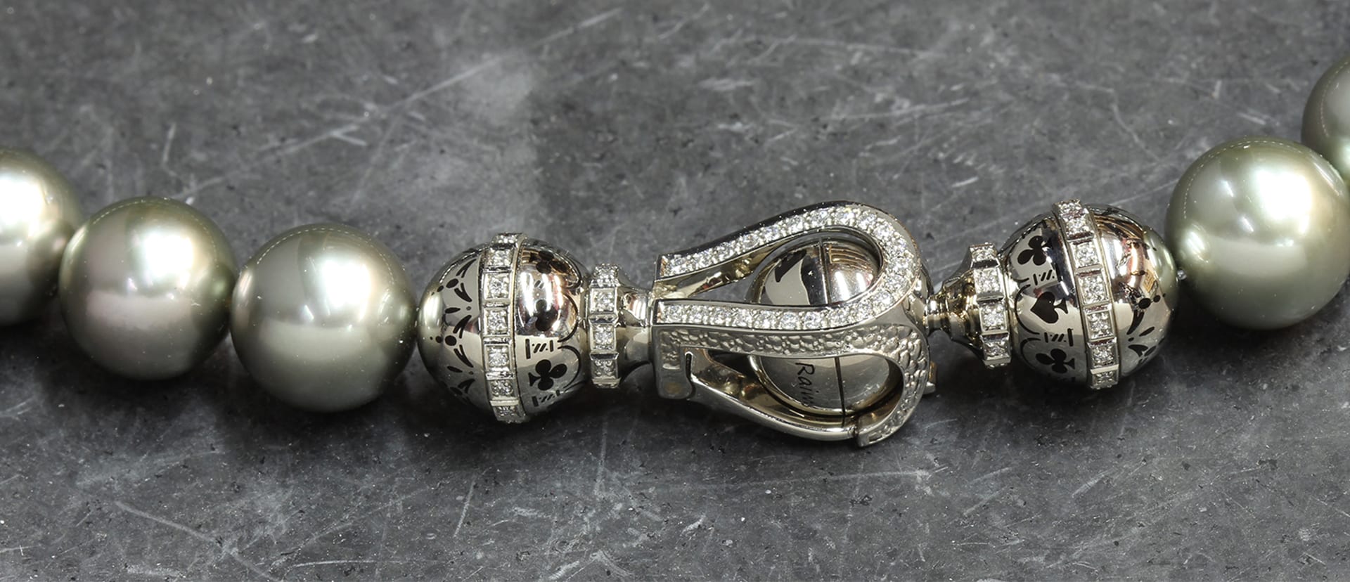 A pearl necklace with an engraved white gold clasp set with diamonds