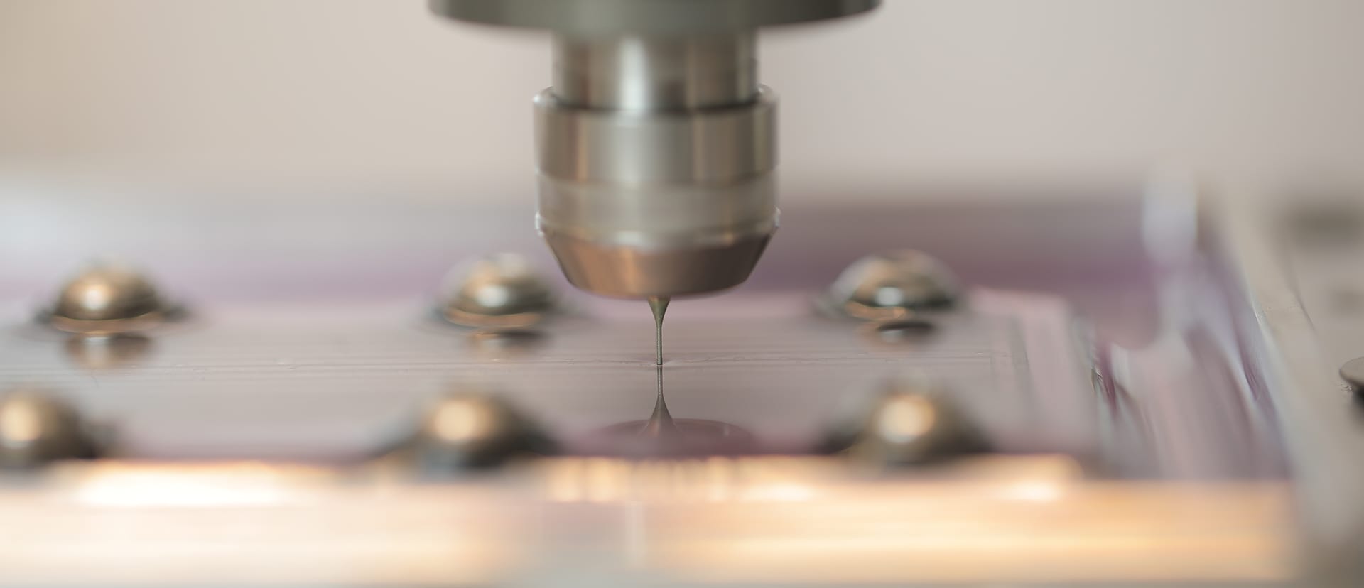 Close-up of a micro end mill touching a machined surface, the spindle nose above it
