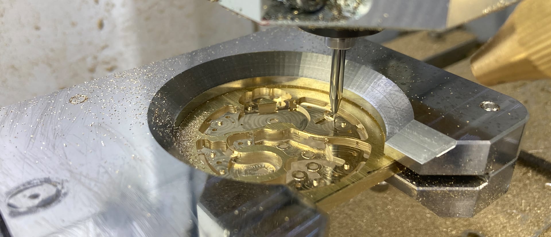 A watch mainplate being milled in brass, fine chips around the cutter