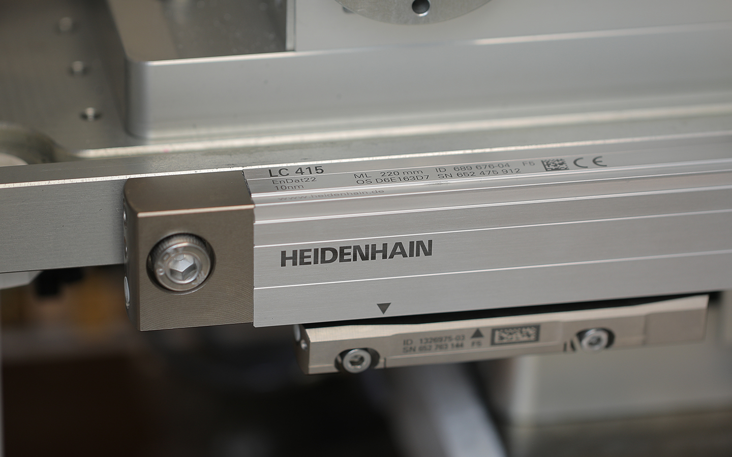 Linear encoder scale fixed along a machine carriage, with a reading head on the moving axis