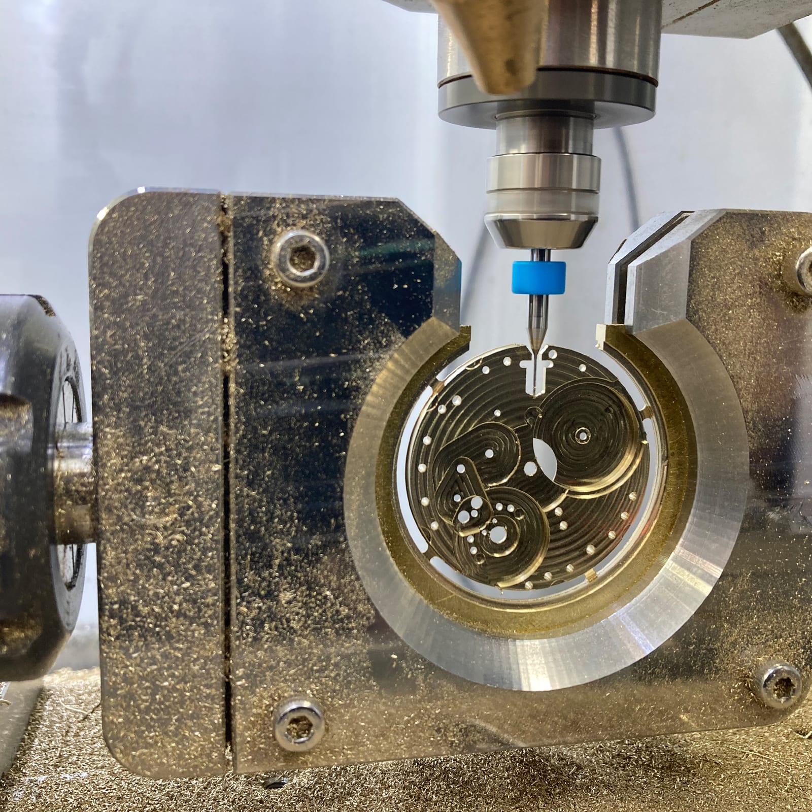A micro end mill cutting a watch movement plate held in a rotary fixture