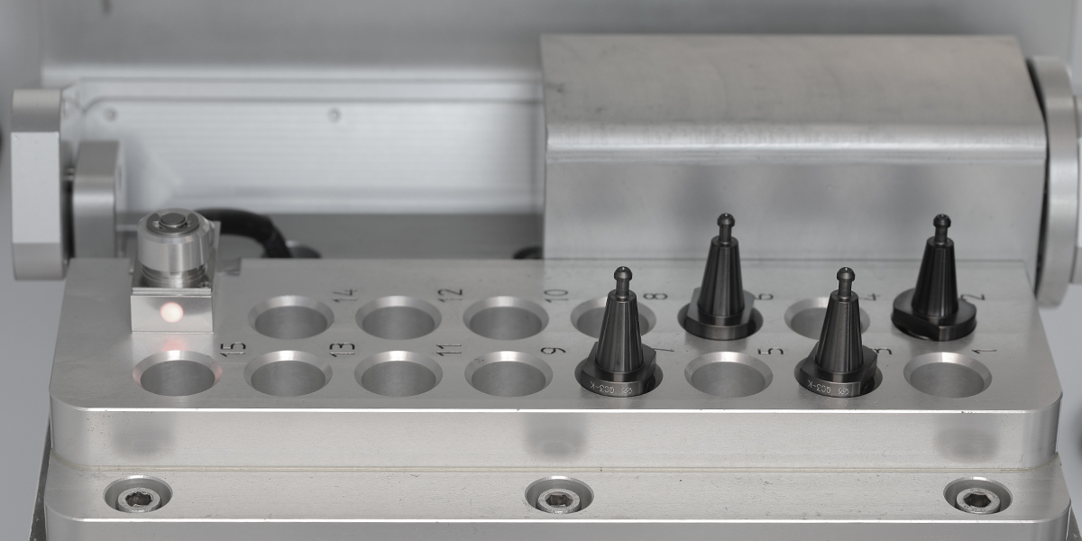 The 15-station tool magazine with numbered stations, taper tool holders seated, and the tool height sensor with its LED indicator at left
