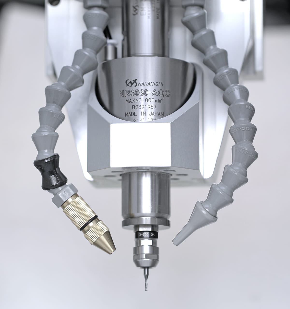 The NSK Nakanishi NR3060-AQC spindle with a tool in the collet chuck, flanked by the coolant nozzle and the air nozzle