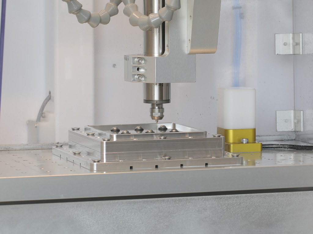 Spindle over an aluminum fixture plate with dome-head screws mounted on the hole-grid table