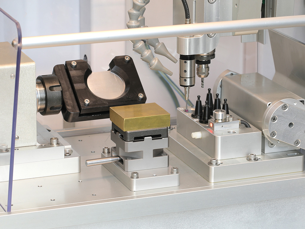 Touch probe in the spindle over a brass block on a pallet vise, with ATC tool pots and the tool-length sensor at right