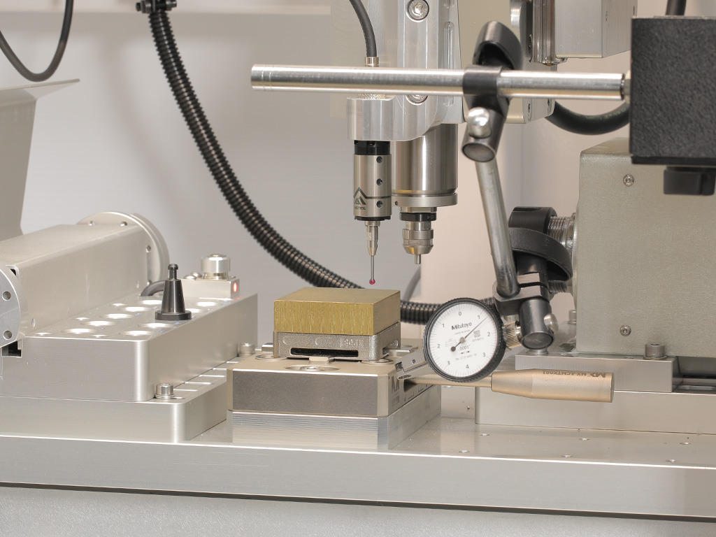 Mitutoyo dial indicator on a holder bar reading off a pallet, with the touch probe and spindle above