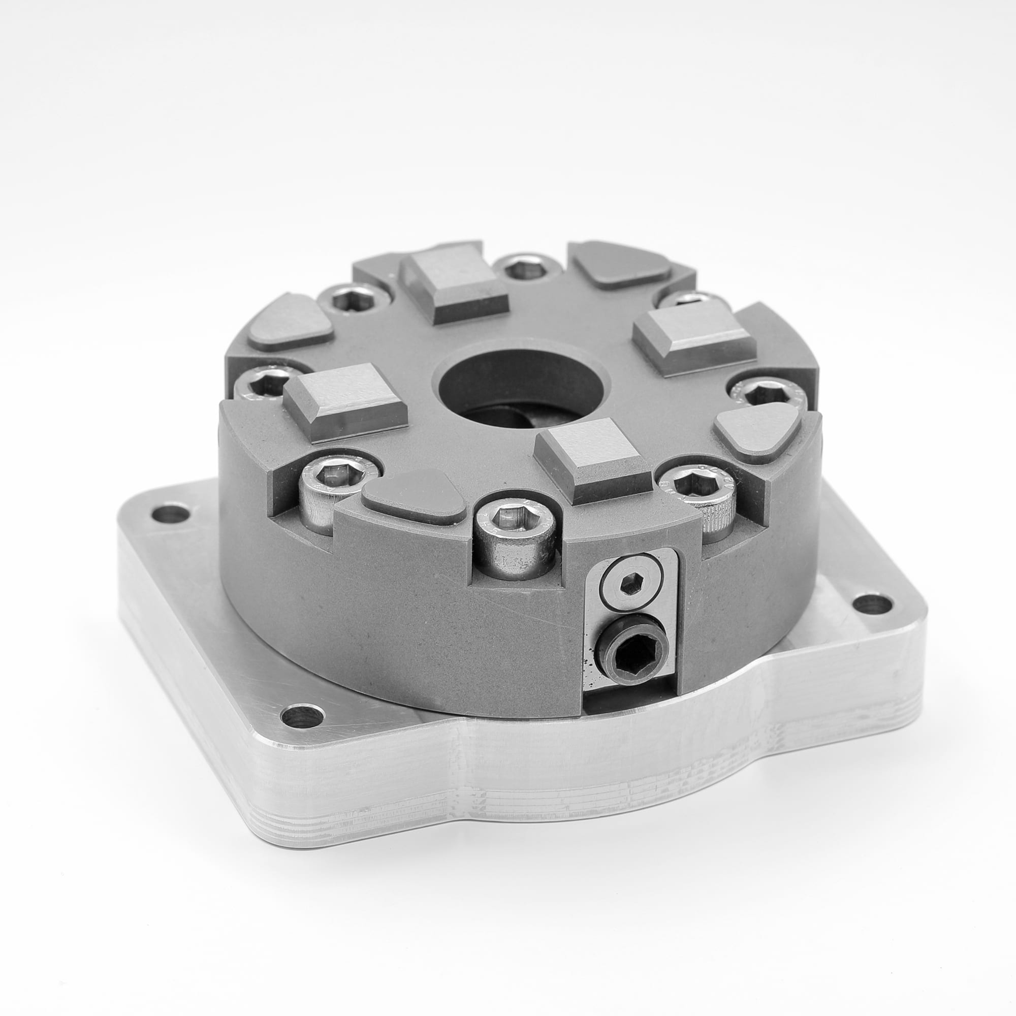 Quick-release chuck base on its mounting plate, eight-lobe top face with hex screws and locating slots, seen from above at an angle