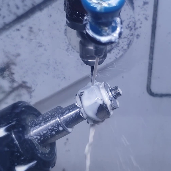 A small metal part on the rotary head being cut under a stream of coolant